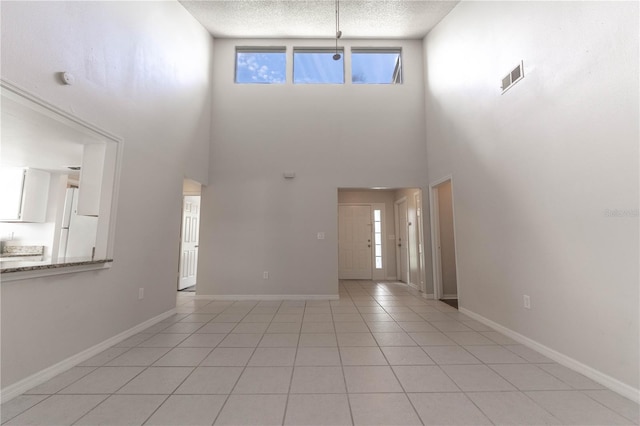 tiled foyer featuring a textured ceiling and a towering ceiling