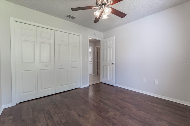 unfurnished bedroom with a closet, a textured ceiling, dark wood-type flooring, and ceiling fan