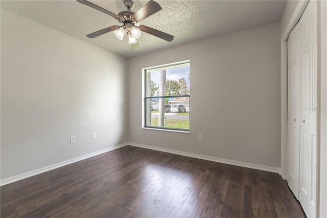 unfurnished bedroom featuring a closet, a textured ceiling, dark wood-type flooring, and ceiling fan