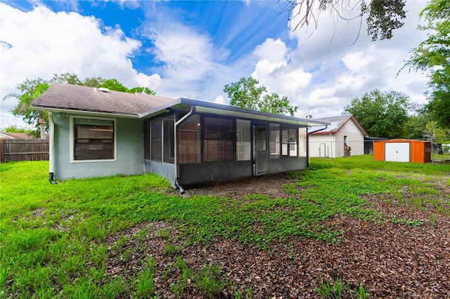 rear view of property featuring a storage unit and a sunroom