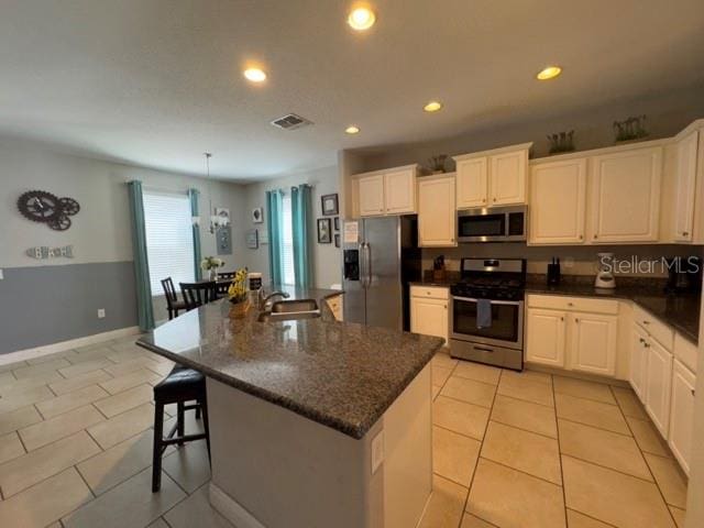 kitchen with white cabinetry, light tile patterned floors, stainless steel appliances, a kitchen island with sink, and sink