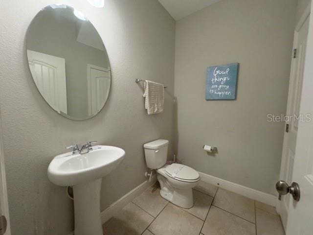 bathroom featuring toilet, tile patterned flooring, and baseboards