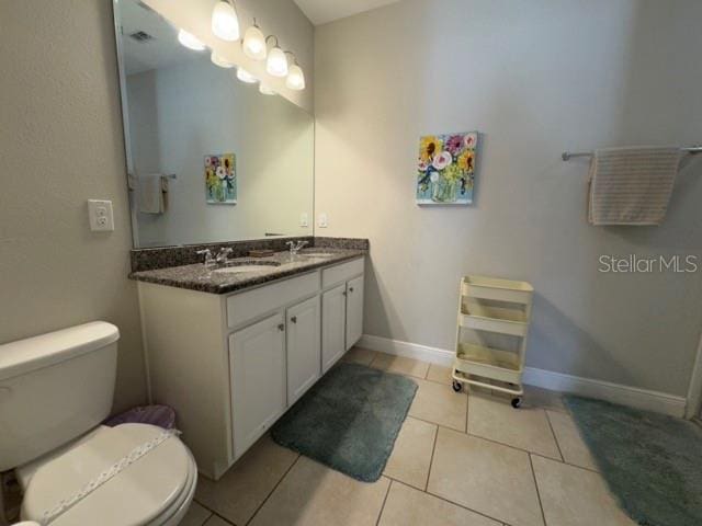 bathroom featuring toilet, double vanity, a sink, and visible vents