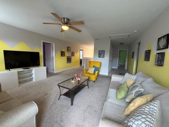 carpeted living room with baseboards, attic access, and a ceiling fan