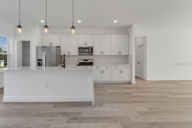 kitchen featuring light hardwood / wood-style flooring, stainless steel appliances, decorative light fixtures, and white cabinets