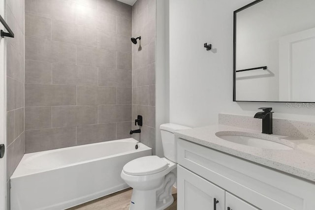 full bathroom featuring tiled shower / bath, vanity, wood-type flooring, and toilet