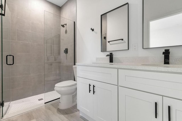 bathroom featuring toilet, walk in shower, vanity, and wood-type flooring