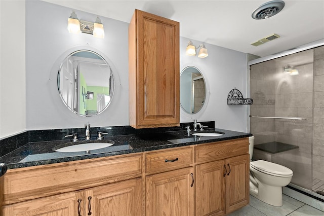 bathroom featuring vanity, toilet, a shower with shower door, and tile patterned flooring