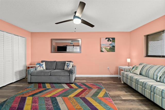 living room with ceiling fan, a textured ceiling, and dark hardwood / wood-style floors