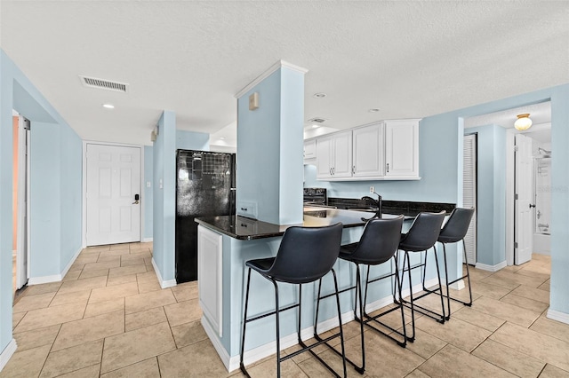 kitchen featuring white cabinetry, sink, kitchen peninsula, a breakfast bar, and light tile patterned floors