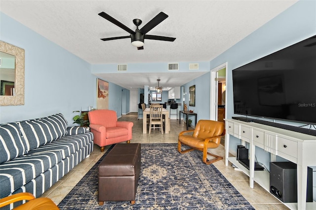 living room with ceiling fan, a textured ceiling, and light tile patterned floors