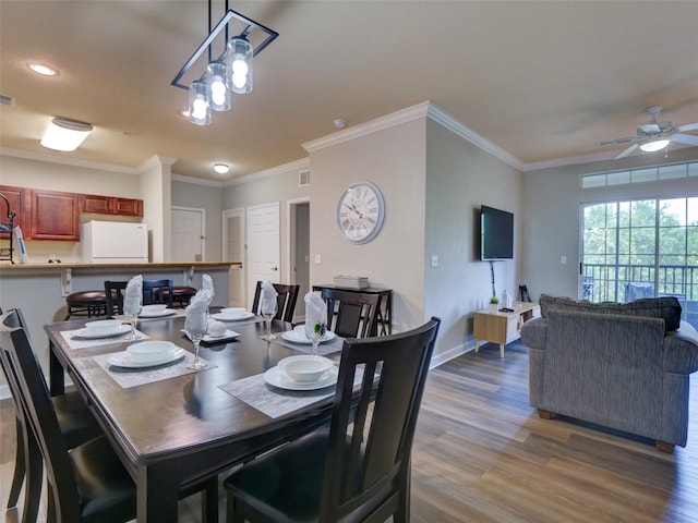 dining space with ceiling fan with notable chandelier, light hardwood / wood-style floors, and ornamental molding