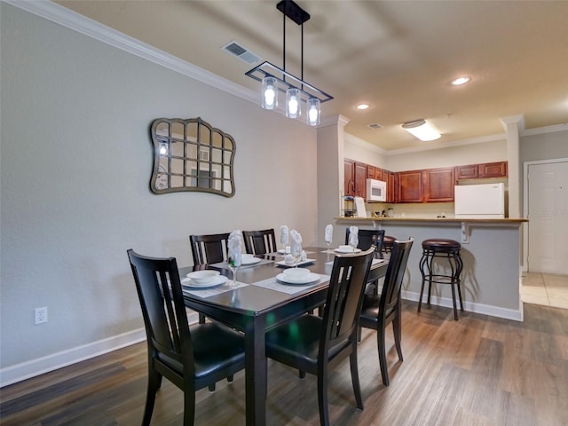 dining room with crown molding and hardwood / wood-style flooring