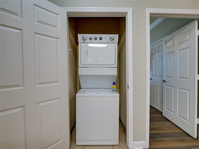 laundry room with hardwood / wood-style floors and stacked washer and clothes dryer