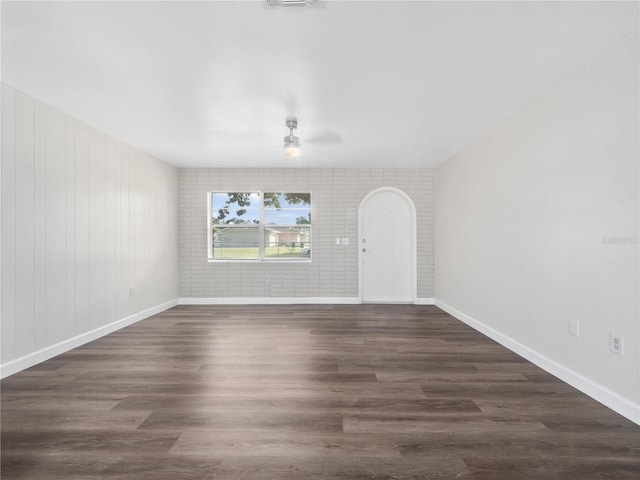 interior space with ceiling fan, brick wall, and dark hardwood / wood-style flooring