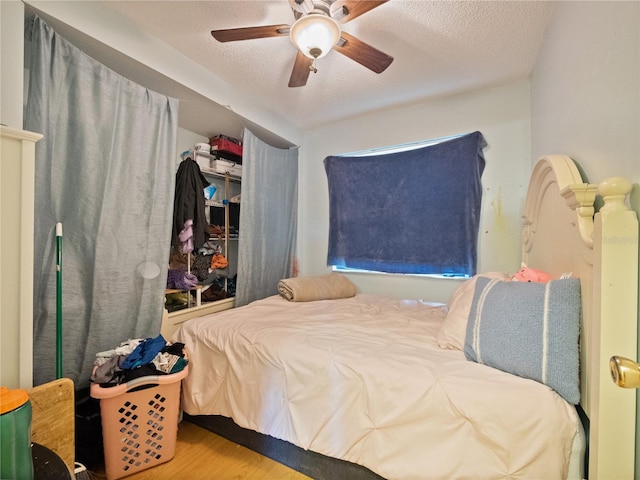 bedroom with a textured ceiling, hardwood / wood-style floors, and ceiling fan