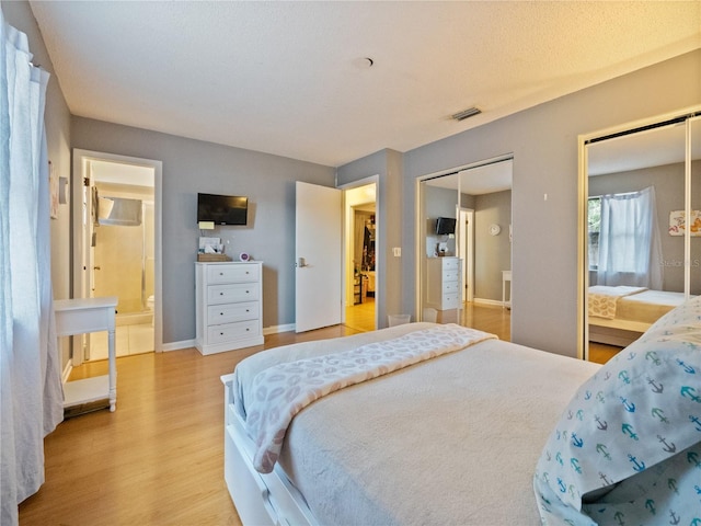 bedroom with ensuite bath and light hardwood / wood-style floors