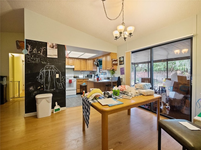 dining room featuring light hardwood / wood-style floors, vaulted ceiling, and a notable chandelier