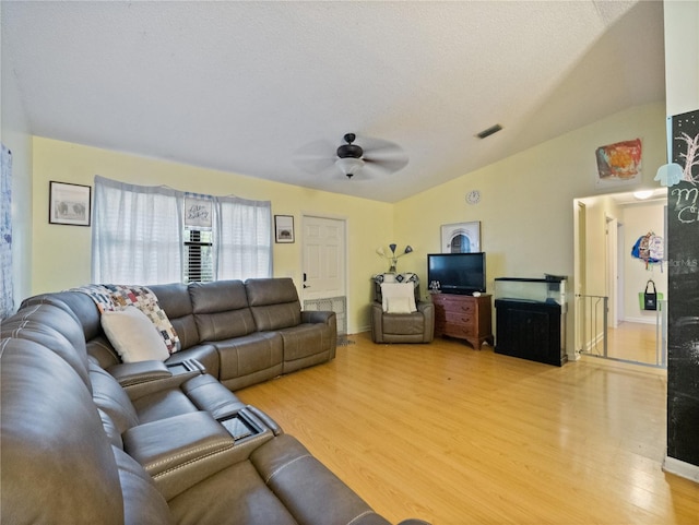 living room with ceiling fan, a textured ceiling, lofted ceiling, and light hardwood / wood-style floors