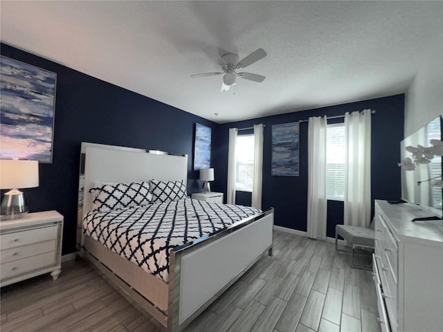 bedroom featuring ceiling fan, light hardwood / wood-style floors, and a textured ceiling