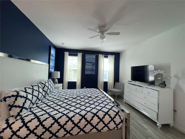 bedroom featuring ceiling fan, light wood-type flooring, and a textured ceiling