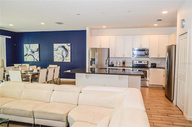 kitchen with a kitchen island, sink, white cabinetry, a breakfast bar area, and stainless steel appliances