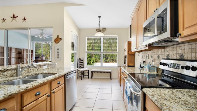 kitchen featuring light tile patterned floors, sink, tasteful backsplash, appliances with stainless steel finishes, and light stone countertops