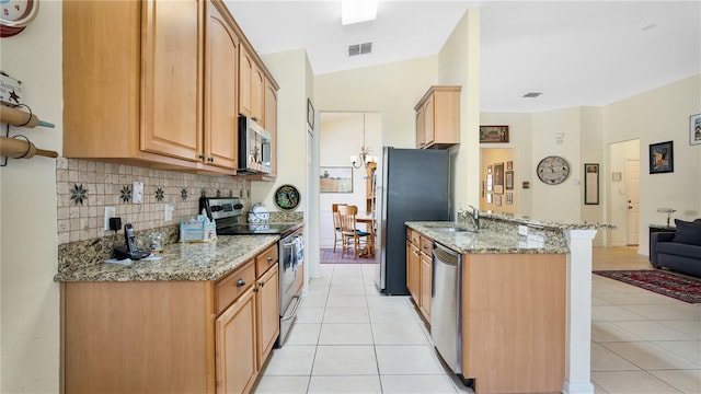 kitchen with appliances with stainless steel finishes, lofted ceiling, light stone countertops, and kitchen peninsula