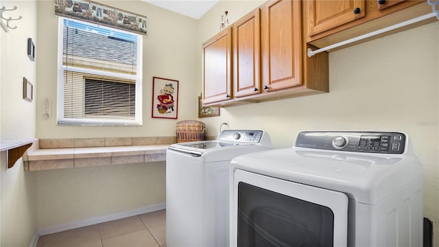 laundry room with washing machine and clothes dryer, light tile patterned floors, and cabinets