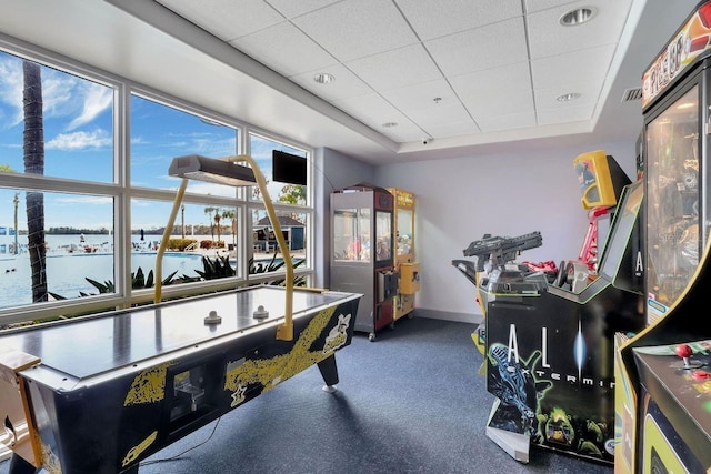 recreation room featuring a water view, a drop ceiling, a tray ceiling, and carpet