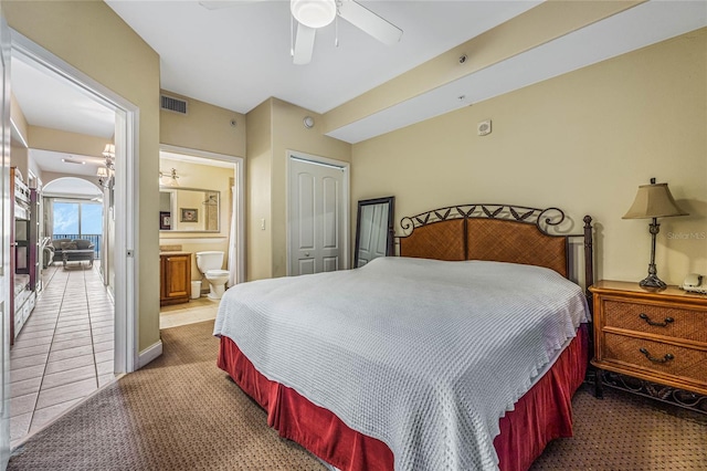 bedroom featuring carpet floors, a closet, ensuite bathroom, and ceiling fan