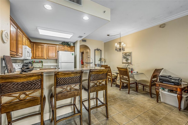 kitchen featuring a chandelier, white appliances, decorative light fixtures, kitchen peninsula, and a kitchen bar