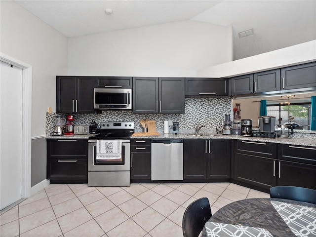 kitchen with light stone counters, light tile patterned flooring, sink, tasteful backsplash, and appliances with stainless steel finishes