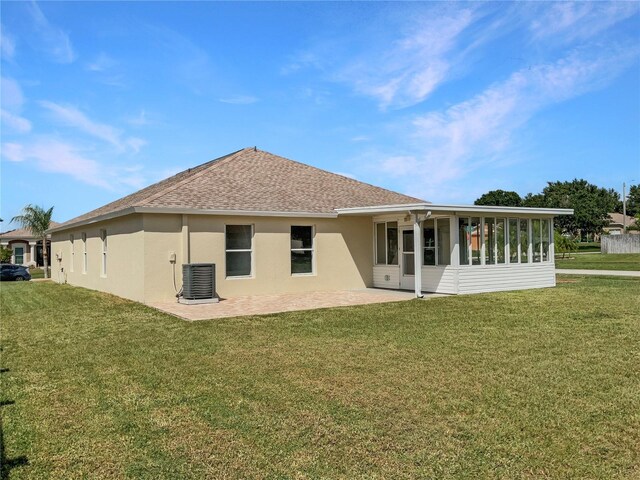 rear view of property featuring a sunroom, a patio, central air condition unit, and a yard