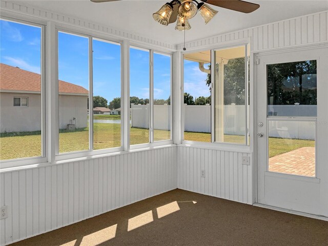 unfurnished sunroom featuring ceiling fan and a wealth of natural light