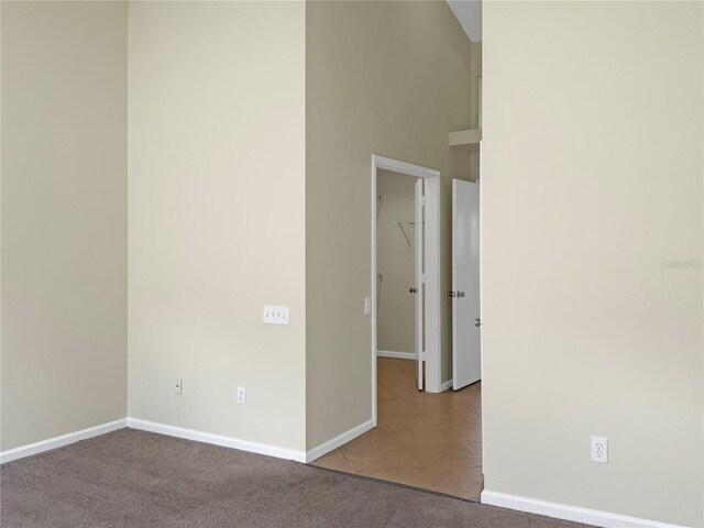 carpeted spare room featuring a towering ceiling