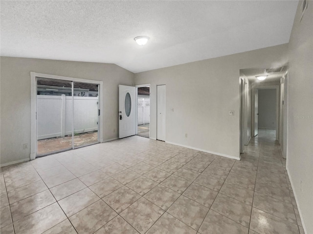 tiled empty room with vaulted ceiling and a textured ceiling