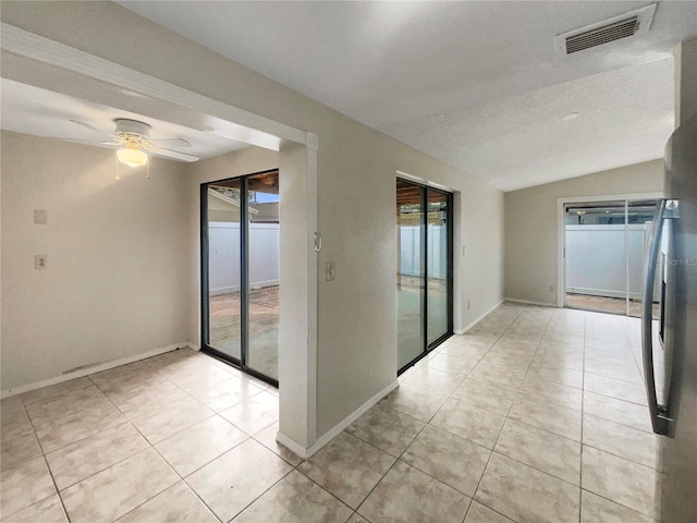 tiled spare room with ceiling fan, a textured ceiling, vaulted ceiling, and a healthy amount of sunlight