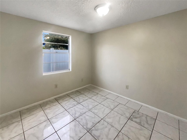 tiled empty room with a textured ceiling