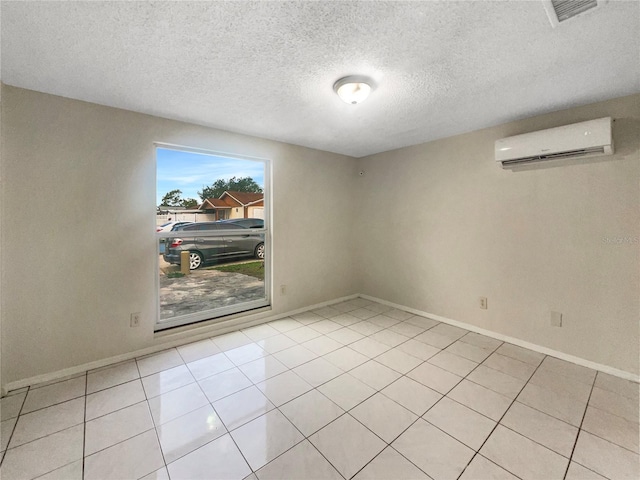 unfurnished room featuring a textured ceiling, an AC wall unit, and light tile patterned floors