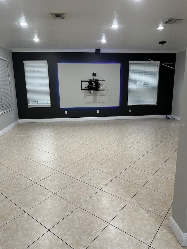 tiled empty room with ornamental molding and a textured ceiling