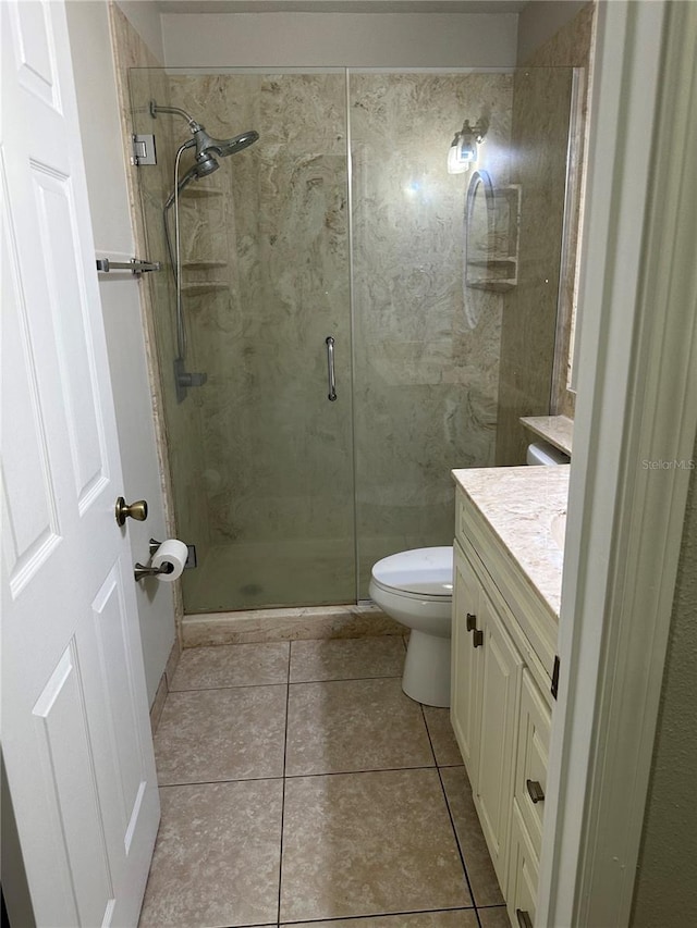 bathroom with tile patterned floors, walk in shower, vanity, and toilet