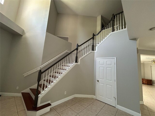 1278 Snug Harbor Dr, Casselberry, FL 32707 - stairs with tile patterned floors, a towering ceiling, a ceiling fan, and baseboards