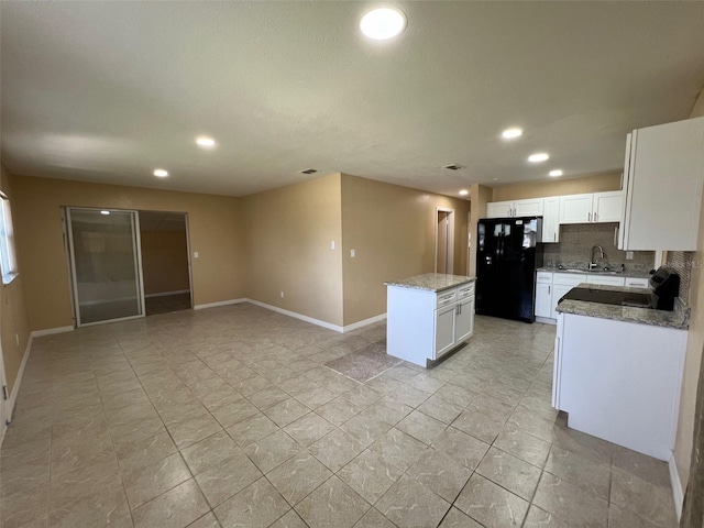 kitchen with light stone counters, a center island, tasteful backsplash, white cabinetry, and black appliances