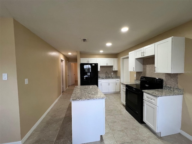 kitchen featuring light stone counters, white cabinets, backsplash, black appliances, and sink