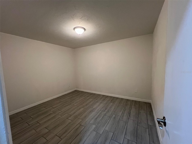 spare room with a textured ceiling and dark hardwood / wood-style flooring