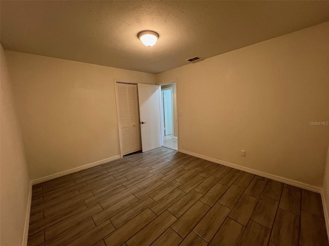 unfurnished room with a textured ceiling and wood-type flooring