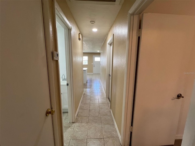 hallway featuring a textured ceiling and light tile patterned floors