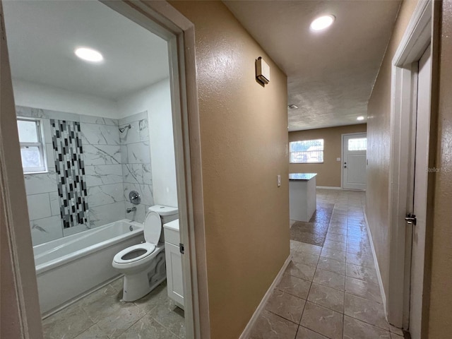 full bathroom with tiled shower / bath, vanity, and toilet