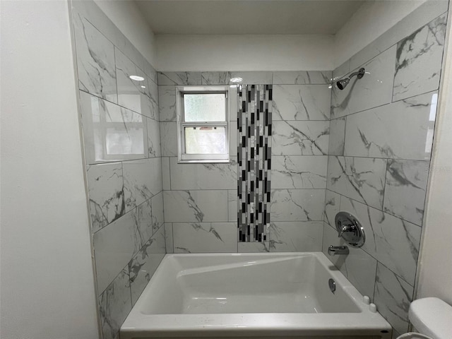 bathroom with tiled shower / bath combo and toilet